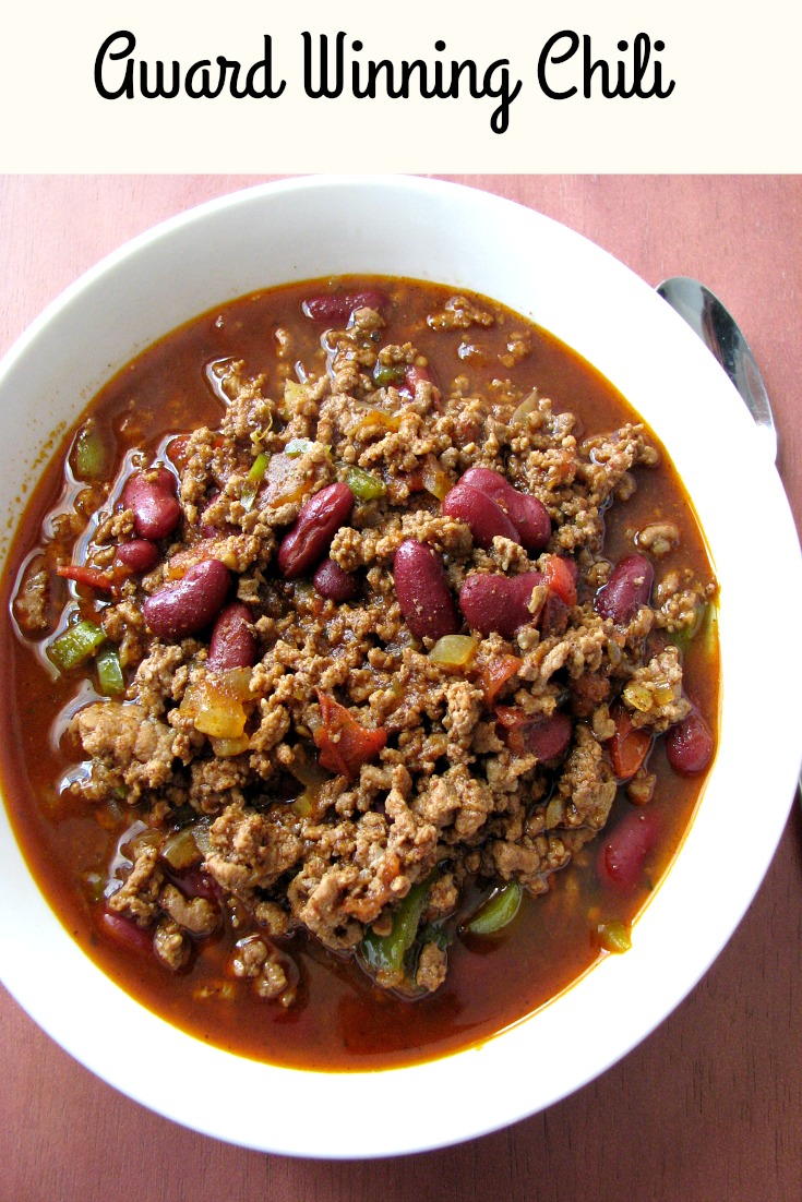 Photo of Award Winning Chili in a white bowl on a wood table with text at the top stating Award Winning Chili