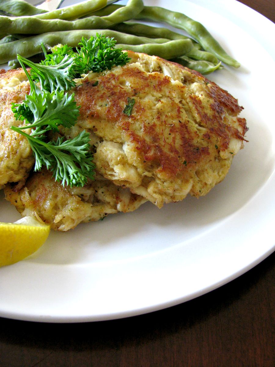 Photo of a plate of crab cakes with green beans in the background