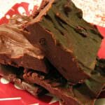 Photo of four pieces chocolate cherry hazelnut fudge on a red and white plate with a white tablecloth with red sprinkles on it