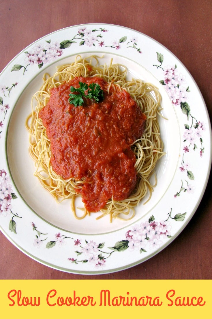 photo of a white flower trimmed plate topped with cooked spaghetti and Slow Cooker Marinara Sauce