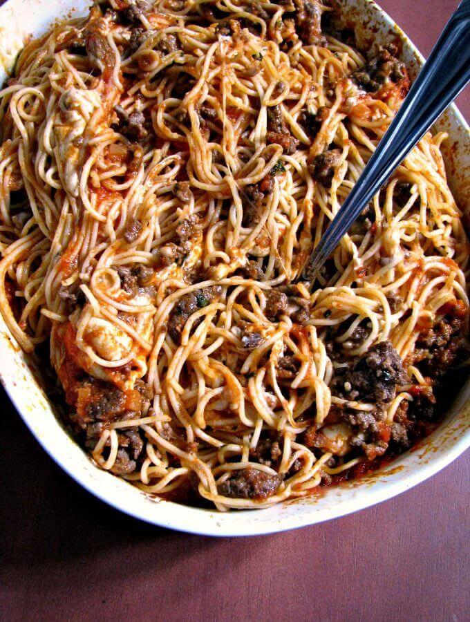 Photo of Leftover Spaghetti Casserole in a white baking dish with a fork stuck in the middle
