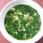 Overhead photo of Spinach Egg Drop Soup in a white bowl on a wood table