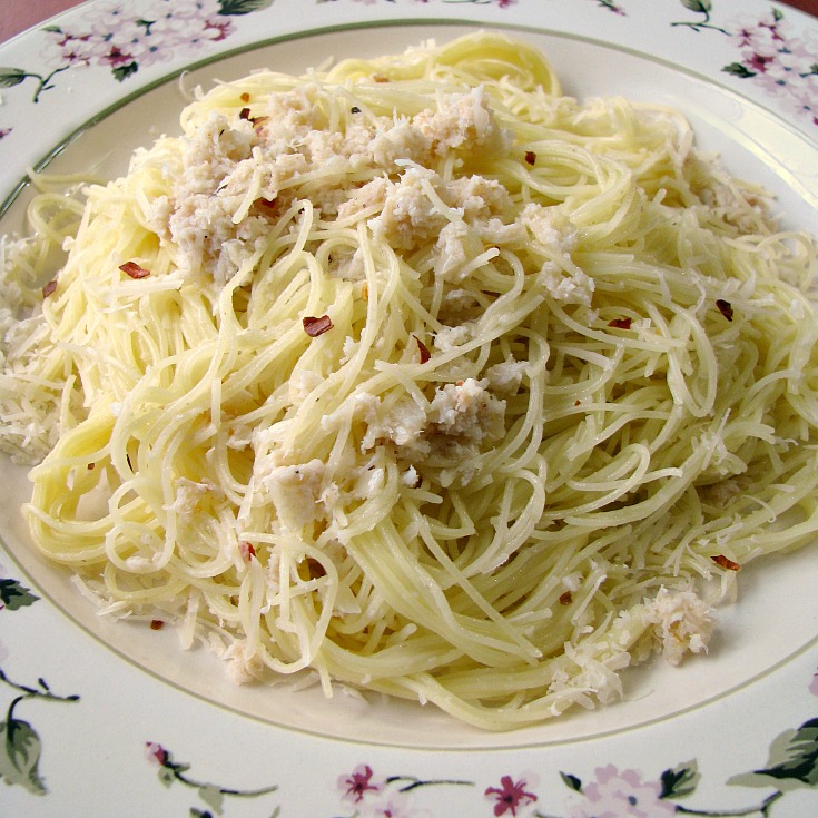 Close up photo of Garlic Butter Crab Pasta on a white plate with flower trim