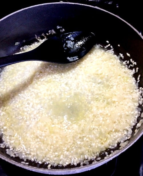 Photo of wine added to rice in a large pan