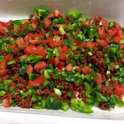 Photo of chorizo topped with tomatoes, peppers, and cilantro