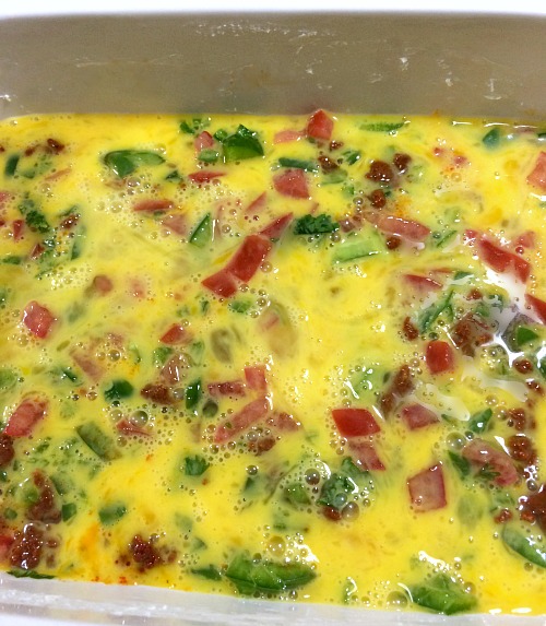 Photo of uncooked eggs, chorizo, and veggies in a baking dish