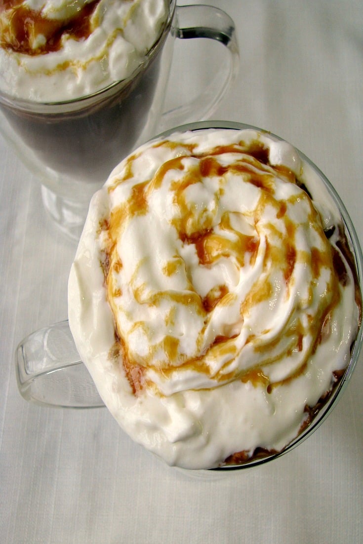 Photo of Salted Caramel Hot Chocolate in two glass mugs on a white tablecloth