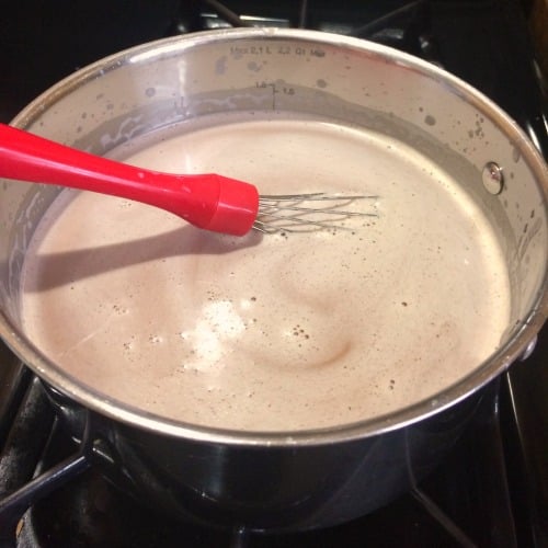 Photo showing melting chocolate in a saucepan with a red handled whisk