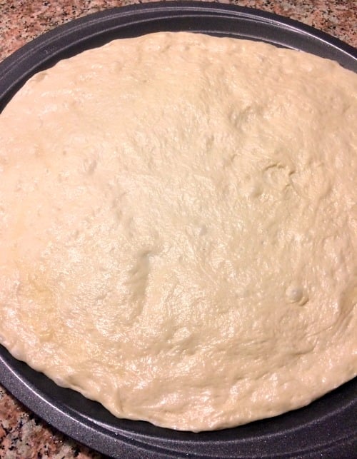Photo of unbaked pizza dough on a pizza pan