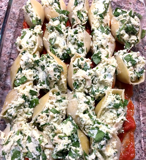 Photo of filled chicken and spinach stuffed shells in a glass baking dish