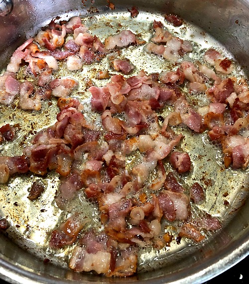 picture of sliced bacon sauteing in a deep skillet