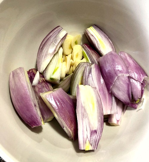 photo of sliced shallots and garlic in a white bowl