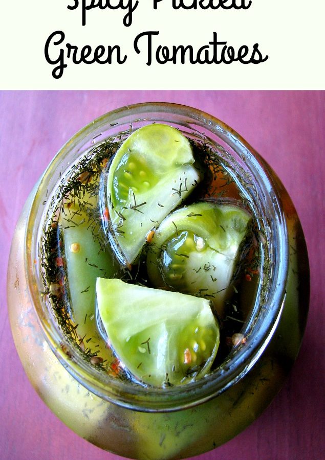 Overhead photo of spicy pickled green tomatoes in a glass jar on a wood table