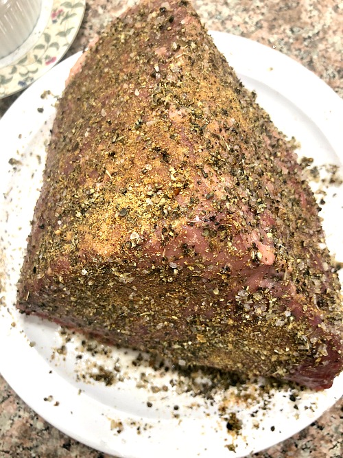 Photo of top round beef coated with olive oil and seasonings on a plate