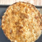 photo of a whole pot pie on a baking sheet on top of a wood table
