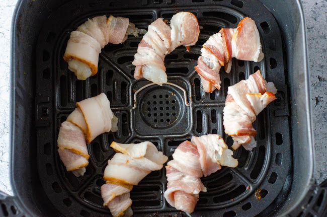 bacon wrapped raw shrimp in the base of an air fryer
